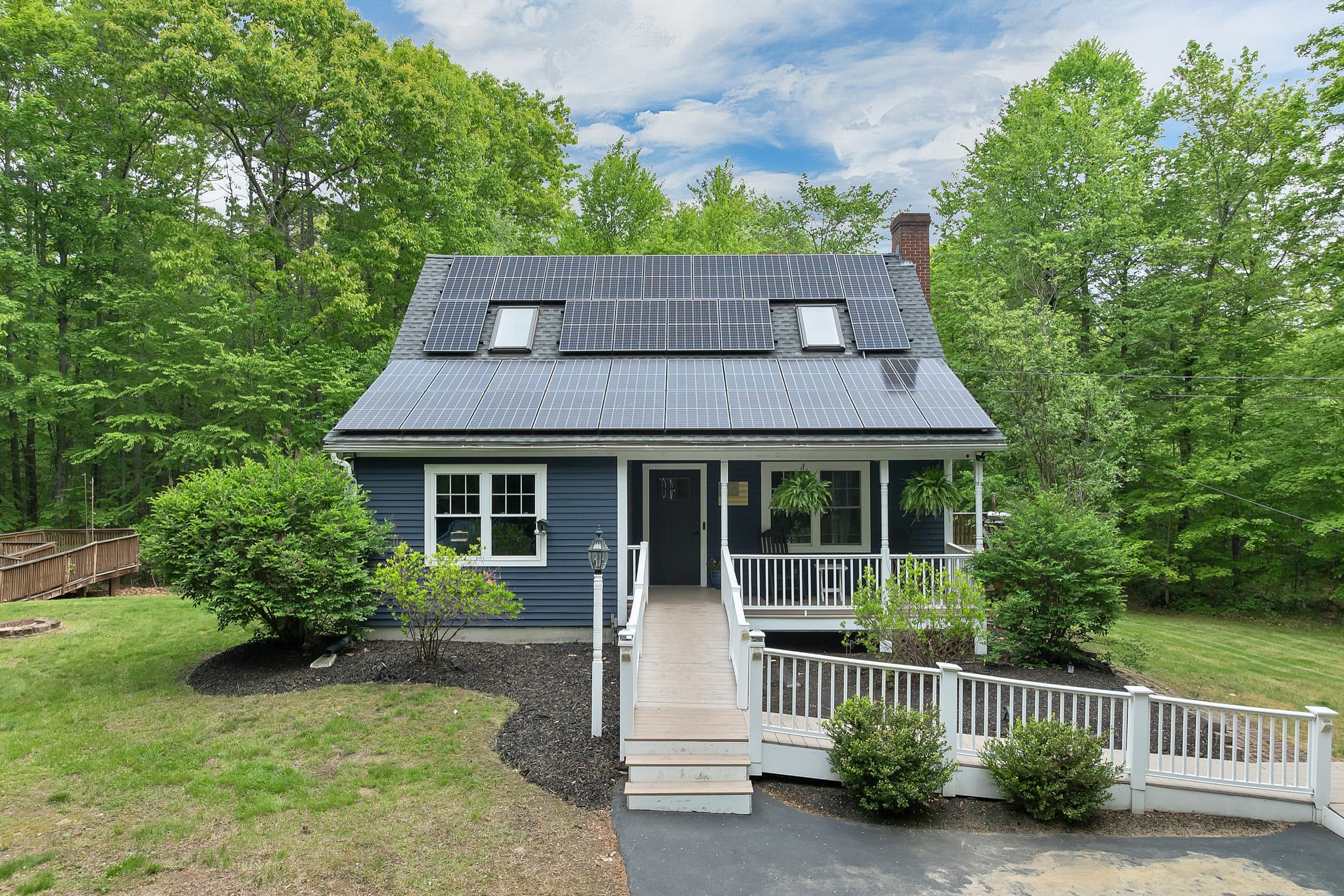 Navy blue Cape with rooftop solar panels and a covered farmer's porch